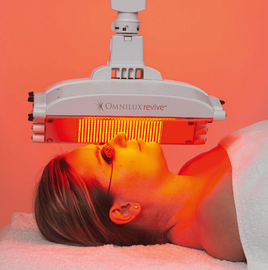 Omnilux Revive Red LED Light therapy. Picture of woman under red led light looking relaxed