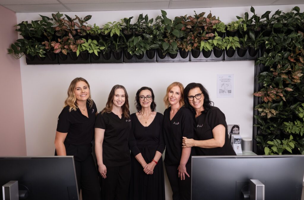 The team at Dr Luci clinic pose in front of the clinic's living wall